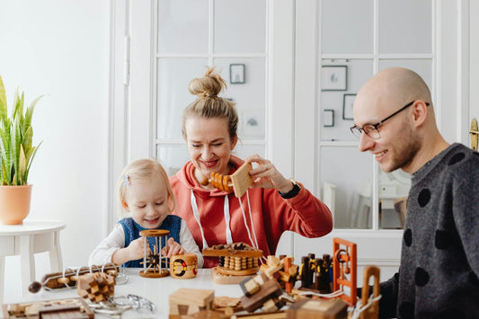 A child and her parents playing with wooden blocks and smiling