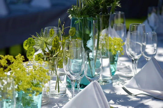Glassware, napkins, silverware, flowers, and a white tablecloth on a table