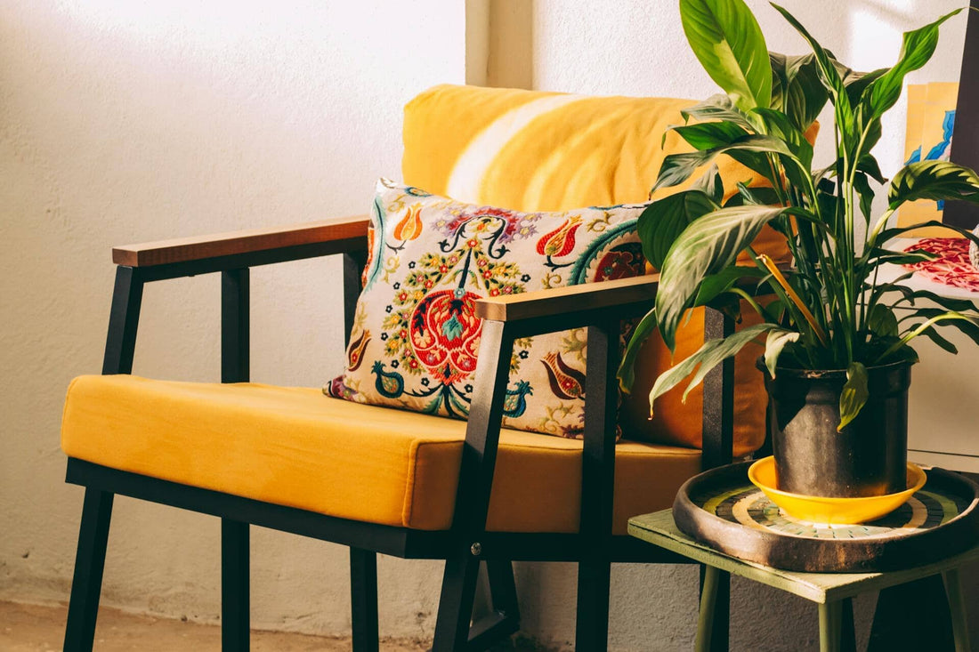 Bright yellow chair with cushion and a green plant