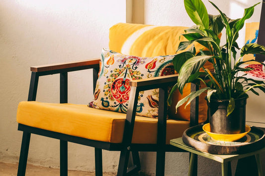 Bright yellow chair with cushion and a green plant