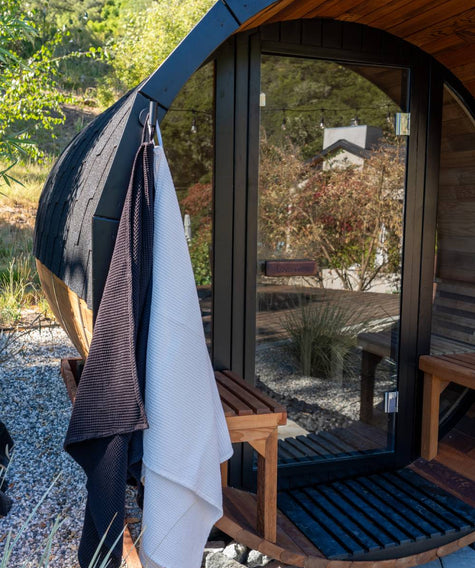 Wooden pod with a towel hanging on a hook, surrounded by greenery