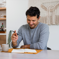 Man writing in journal with coffee cup
