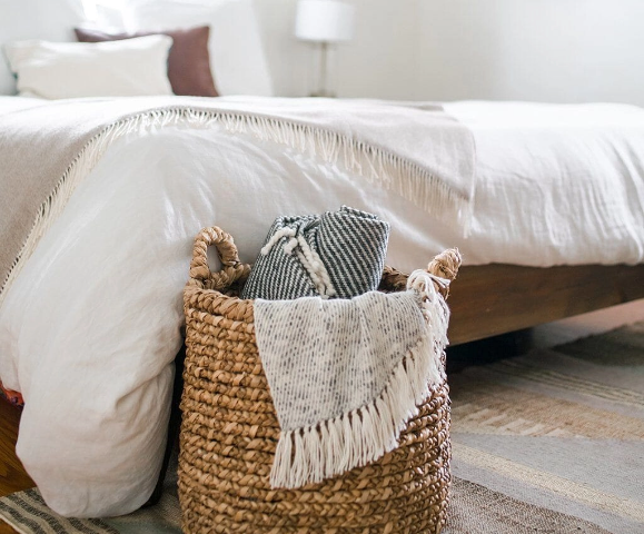 Basket holding throw blankets at the foot of a bed