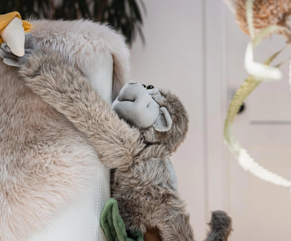 Plush monkey hanging off the edge of a chair